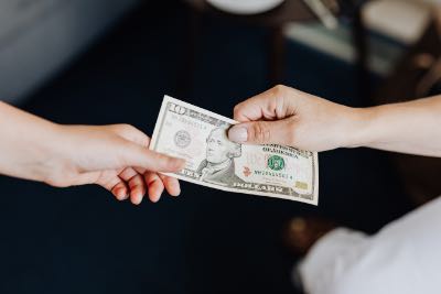 top shot of a $10 bill being passed between two hands.