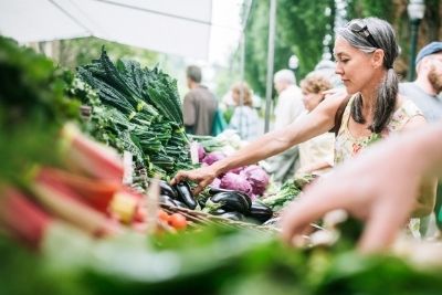 A woman selecting produce at an outdoor farmers market