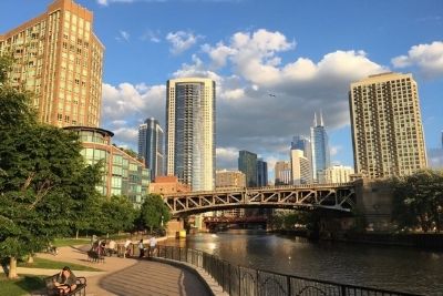 Riverwalk in Mongomery (Ward) Park, a bridge in the midground of the photo, and several skyscapers in the background