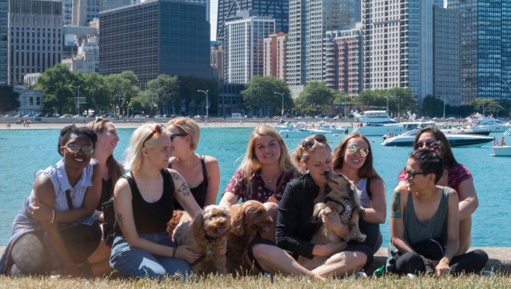 Chicago Urban Pets team with their dogs along the lakefront, with the city skyline behind them.
